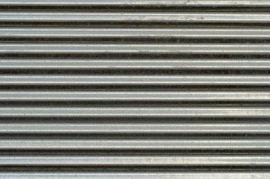 Metal duvar dokusu, arka plan. Yapılar için tırtıklı galvanize metal levha. Yüzeyde sertlik için yatay çıkıntılı kaburgalar var. Çit yapımında çatıları örtmek için kullanılır.