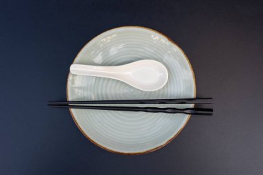 Asya lokantasında boş tabak, kaşık ve çubuklar siyah masada, yakın plan, üst manzara. Tablo ayarı