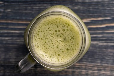 Avokado, kivi, muz, bal, dereotu ve maydanozdan taze yeşil smoothie, ahşap arka planda cam bardak, yakın plan, üst manzara. Sağlıklı beslenme kavramı