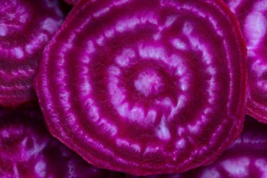 Kırmızı pancar dilimi yakın çekim. Mor pancar, hamurun dokusuyla ikiye bölünmüş. Pancar dilimleri arka plan, üst görünüm