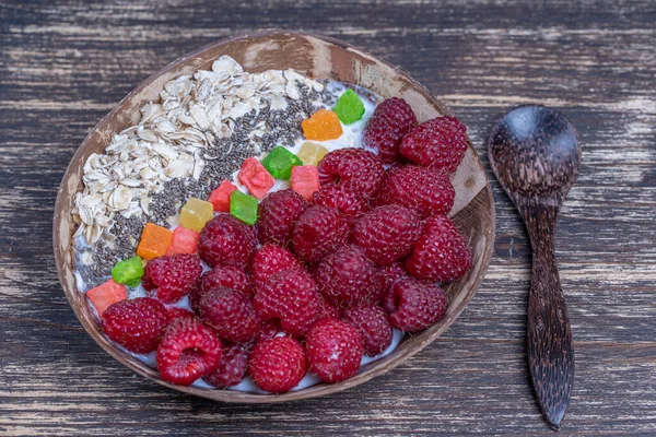 在椰子碗中加入覆盆子 燕麦片 糖果仁和奇亚种子作为早餐 健康饮食的概念 超级食物 顶部视图 — 图库照片