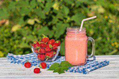 Çilek, ahududu ve muzdan yapılmış bir bardak meyve suyu karışımı. Kapalı, açık havada.