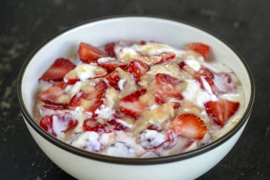 Kırmızı çilek ve beyaz yoğurt. Kahvaltıda meyveli tatlı ve mükemmel olgunlukta çilek, yakın çekim.