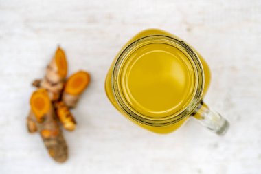 Zerdeçal, zencefil, limon ve ballı enerji içeceği cam bardakta, doğa arka planında, yakın plan, üst görüş. Sağlıklı beslenme kavramı