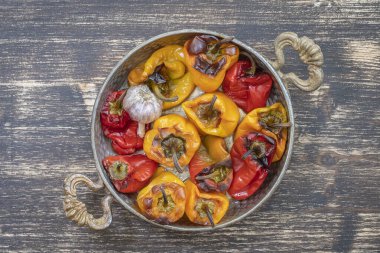Fırınlanmış kırmızı ve sarı dolmalık biber. Biberler ahşap bir masada fırın kabında. Sağlıklı ve lezzetli bir vejetaryen yemeği. Kapat, üst görünüm