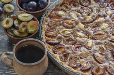 Ev yapımı organik erikli turta yenmeye hazır. Eski ahşap arka planda erik turtası ve fincan sıcak çay, kapatın.