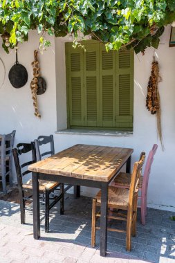 Dışarıdaki küçük kafenin ön manzarası. Beyaz duvarın yanında masa ve boş sandalyeler. Turistik yerler. Tipik Akdeniz restoranı, yazın tatil yapılan bir yer. Kos Adası, Yunanistan