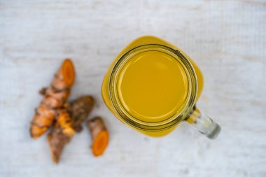 Zerdeçal, zencefil, limon ve ballı cam bardak, beyaz ahşap arka plan, yakın çekim, üst görüş. Sağlıklı beslenme kavramı