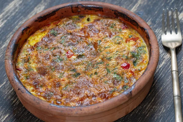 Sebzeli frittata ile seramik kase, basit vejetaryen yemeği. Tahta masada domates, biber, soğan ve peynirli frittata, yakın çekim. İtalyan omleti, üst manzara.