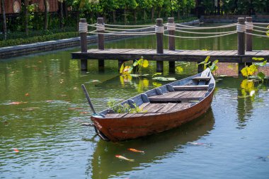 Danang, Vietnam 'daki tropik bir bahçedeki iskelenin yakınındaki gölette tahta bir tekne. Seyahat ve doğa kavramı