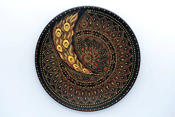 Decorative ceramic plate with black, red and golden colors, painted plate on white background, close up, top view. Decorative porcelain plate painted with acrylic paints, handwork, dot painting