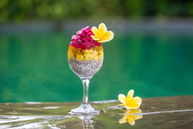 Kırmızı ejderha meyveli Chia tohumu pudingi, çarkıfelek meyvesi, mango ve avokado kahvaltıda yüzme havuzu suyunun arka planında, yakın çekim. Sağlıklı beslenme kavramı.