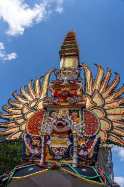 Endonezya 'nın Bali Adası' ndaki merkez caddede geleneksel iblis ve çiçek heykelleri bulunan Bade yakma kulesi. Yaklaşan yakma töreni için hazır. Kapat.