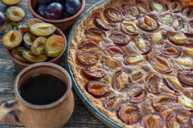 Ev yapımı organik erikli turta yenmeye hazır. Eski ahşap arka planda erik turtası ve fincan sıcak çay, kapatın.