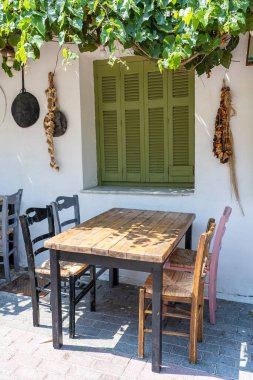 Dışarıdaki küçük kafenin ön manzarası. Beyaz duvarın yanında masa ve boş sandalyeler. Turistik yerler. Tipik Akdeniz restoranı, yazın tatil yapılan bir yer. Kos Adası, Yunanistan
