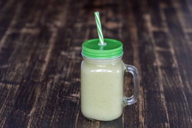 Avokado 'dan taze yeşil smoothie, ahşap arka planda cam bardakta muz ve bal, yakın plan. Sağlıklı beslenme kavramı