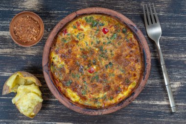 Sebzeli frittata ile seramik kase, basit vejetaryen yemeği. Tahta masada domates, biber, soğan ve peynirli frittata, yakın çekim. İtalyan omleti, üst manzara.