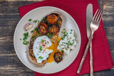 Kızarmış kırmızı domatesli haşlanmış yumurta, tabakta sarımsak ve süzme peynir, yakın çekim, üst manzara