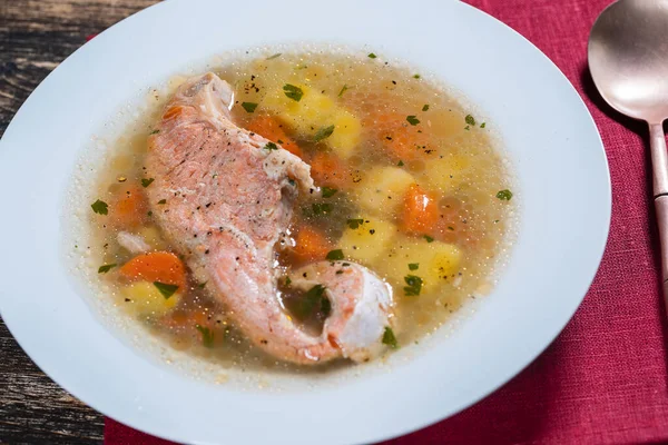 新鮮なサーモンの魚のスープ ニンジン ジャガイモ ハーブを白いプレートに入れ 閉じます おいしいディナーは魚のスープとサーモンで構成されています — ストック写真