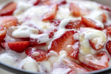 Kırmızı çilek ve beyaz yoğurt. Kahvaltıda meyveli tatlı ve mükemmel olgunlukta çilek, yakın çekim.