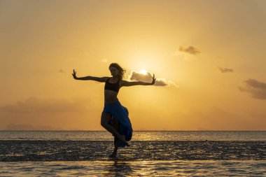 Gün batımında cennet adasındaki tropikal sahilde dans eden genç güzel kız, kapat. Yaz kavramı. Tatil seyahati.