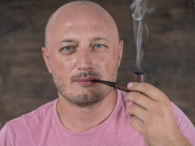 Pipo içen adam. İçerde orta yaşlı bir adamın portresi. Kötü alışkanlıklar, bağımlılık. Sağlıksız yaşam tarzı kavramı. Kapat.