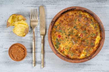 Sebzeli frittata ile seramik kase, basit vejetaryen yemeği. Tahta masada domates, biber, soğan ve peynirli frittata, yakın çekim. İtalyan omleti, üst manzara.