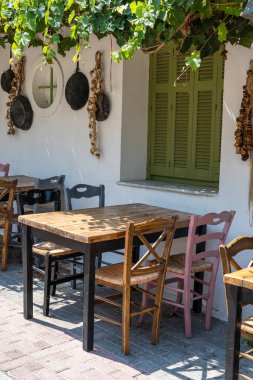 Dışarıdaki küçük kafenin ön manzarası. Beyaz duvarın yanında masa ve boş sandalyeler. Turistik yerler. Tipik Akdeniz restoranı, yazın tatil yapılan bir yer. Kos Adası, Yunanistan