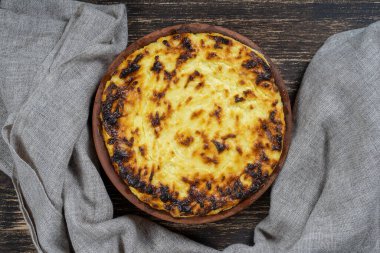 Kuru üzümlü ve ahşap masadaki irmikli süzme peynir güveci güzelmiş. Fırında pişmiş peynirli güveç ile seramik kase, yakın çekim, üst manzara.