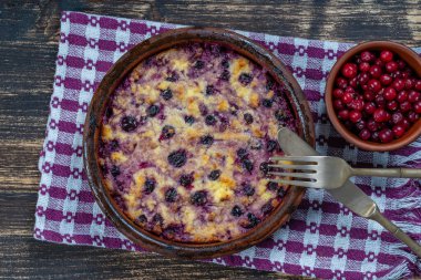 Siyah frenk üzümü ve ahşap masada irmik ile süzme peynir güveci. Fırında pişmiş peynirli güveç ile seramik kase, kapat.