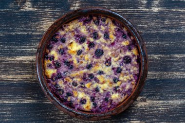 Siyah frenk üzümü ve ahşap masada irmik ile süzme peynir güveci. Fırında pişmiş peynirli güveç ile seramik kase, kapat.