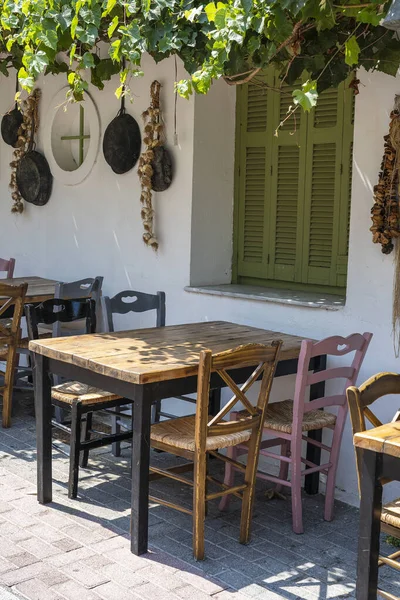 Dışarıdaki küçük kafenin ön manzarası. Beyaz duvarın yanında masa ve boş sandalyeler. Turistik yerler. Tipik Akdeniz restoranı, yazın tatil yapılan bir yer. Kos Adası, Yunanistan