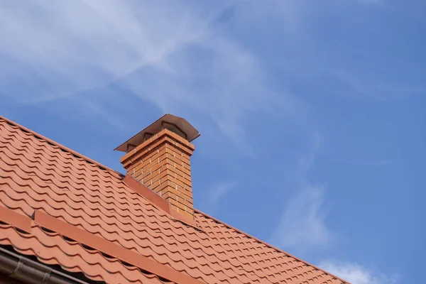 青い空に対する戸建ての家と煙突の赤い屋根を閉じます — ストック写真