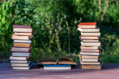Ahşap masanın üzerine kitap yığını. Arka plan, açık hava. Kapatın.