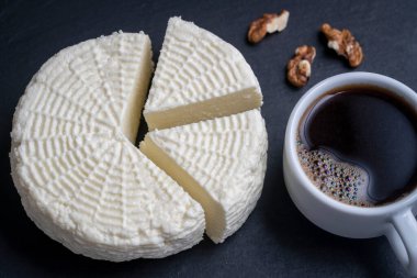 Beyaz fincanlı ev yapımı beyaz peynir ve siyah arka planda ceviz, yakın plan, üst manzara. Ev yapımı peynir. Sütten peynir.