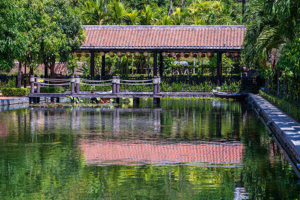 Wooden pier on pond in a tropical garden in Danang, Vietnam. Travel and nature concept