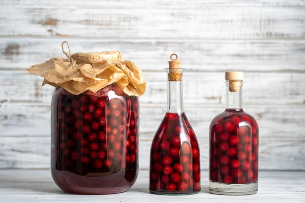 赤チェリーの自家製チンキ ベリーアルコール飲料のコンセプト 白木製の背景にガラス瓶や瓶で熟したチェリーから作られた自家製の赤ワイン ウクライナ — ストック写真