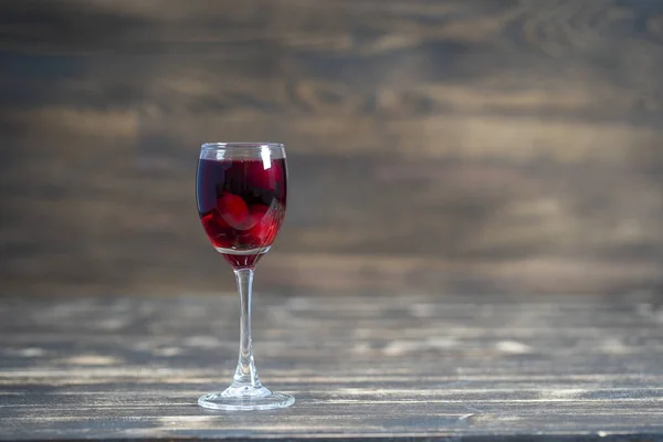 赤チェリーの自家製チンキ ベリーアルコール飲料のコンセプト 木製の背景にあるワイングラスで熟したチェリーから作られた自家製の赤ワイン ウクライナ 閉じる コピースペース — ストック写真