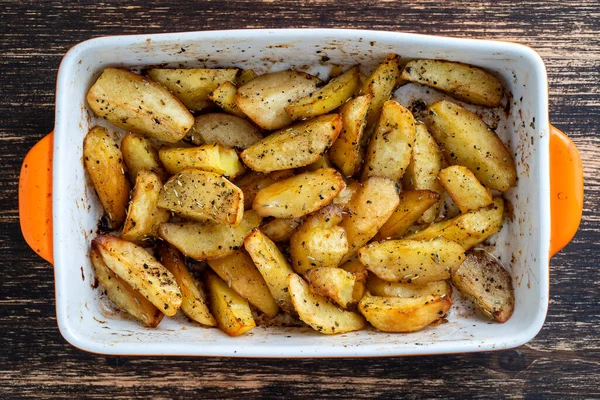 Ukrainian national dish is baked potatoes, close up. Ceramic bowl with potato slices background, top view