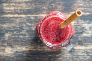 Cam kavanozda taze böğürtlen püresi ve ahşap arka planda bambu kamışı. Üst Manzara, kapat, kopyala alanı. Sağlıklı gıda konsepti