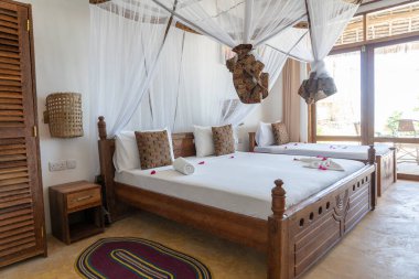 Lüks gösteriler için dekore edilmiş dört poster yataklı bir yazlık yatak odası. Doğu Afrika 'nın Zanzibar adasındaki tropikal villanın iç tasarımı