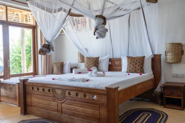 Lüks gösteriler için dekore edilmiş dört poster yataklı bir yazlık yatak odası. Doğu Afrika 'nın Zanzibar adasındaki tropikal villanın iç tasarımı
