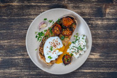 Kızarmış kırmızı domatesli haşlanmış yumurta, tabakta sarımsak ve süzme peynir, yakın çekim, üst manzara