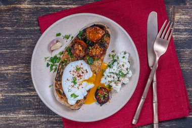 Kızarmış kırmızı domatesli haşlanmış yumurta, tabakta sarımsak ve süzme peynir, yakın çekim, üst manzara