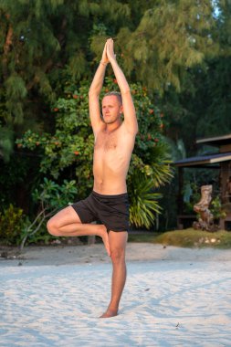 Rastalı genç adam tropik bir plajda yoga yapıyor, yakın çekim. Sağlıklı yaşam tarzı kavramı