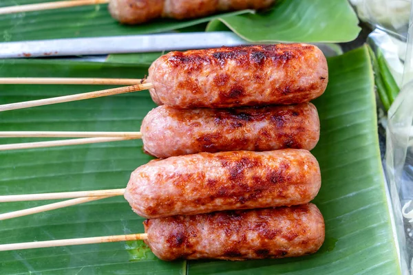 Grilled Thai sausage at street food market in Thailand, close up. Traditional Thai sausage with pork and rice, delicious street food.