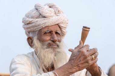 PUSHKAR, INDIA - 15 Kasım 2018: Hindistan 'ın kutsal şehri Pushkar, Rajasthan yakınlarındaki Pushkar Camel Mela sırasında çöldeki Hintli adam. Bu fuar dünyanın en büyük deve ticaret fuarı..