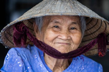 Nha Trang, Vietnam - 30 Mart 2020: Nha Trang, Vietnam 'da bir sokak pazarında yüzünde gülümseme olan etnik yaşlı kadın