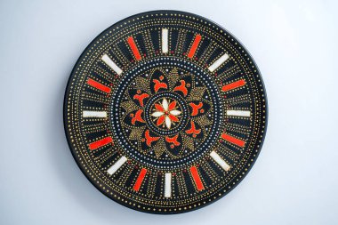 Kırmızı ve altın renkli dekoratif seramik plaka, beyaz arka planda boyanmış plaka, yakın plan, üst manzara. Akrilik boyalarla boyanmış dekoratif porselen tabaka, el işi, nokta boyası.