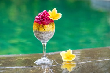 Kırmızı ejderha meyveli Chia tohumu pudingi, çarkıfelek meyvesi, mango ve avokado kahvaltıda yüzme havuzu suyunun arka planında, yakın çekim. Sağlıklı beslenme kavramı.